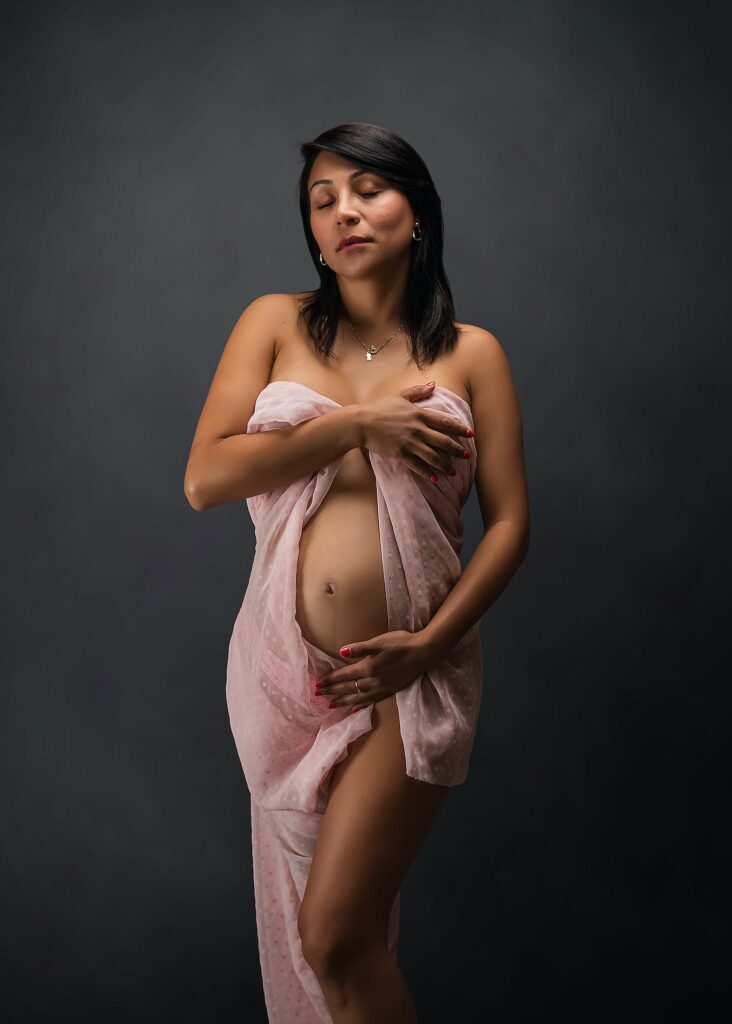 A pregnant woman in a pink towel posing for a photo