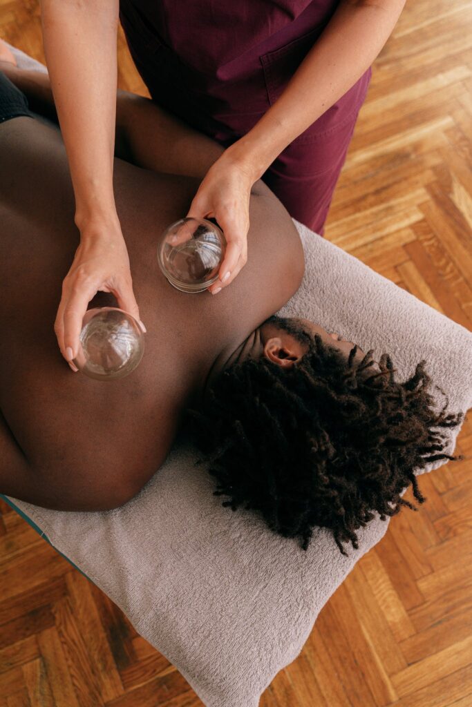 Woman Placing Glass Cups On A Man's Back